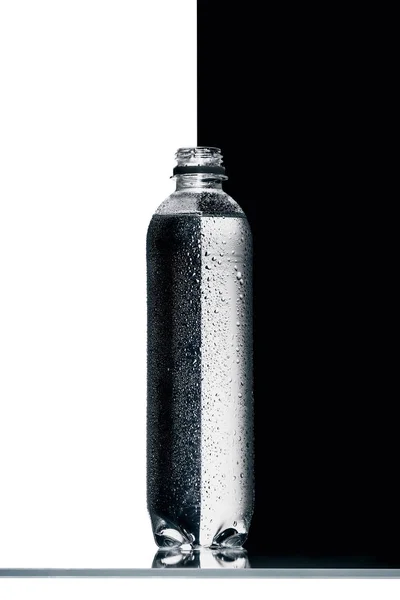 Plastic bottle of water on half black and white background — Stock Photo