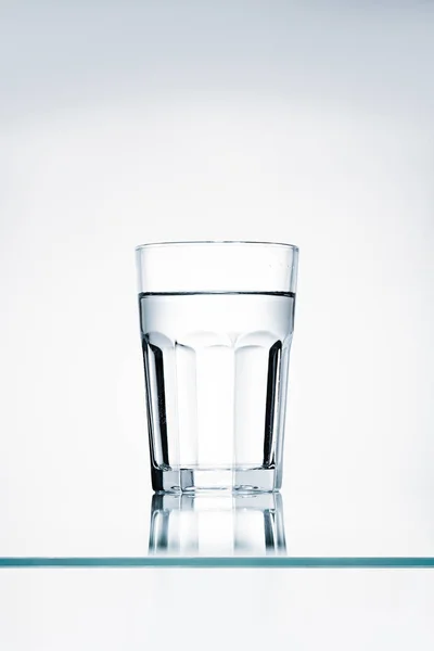 Glass fn clear water on reflective surface — Stock Photo