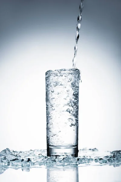 Cold water pouring into glass on white — Stock Photo