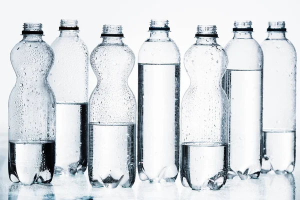 Plastic bottles of water in row isolated on white — Stock Photo