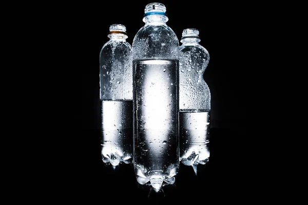 Varie bottiglie di plastica di acqua sul buio — Foto stock