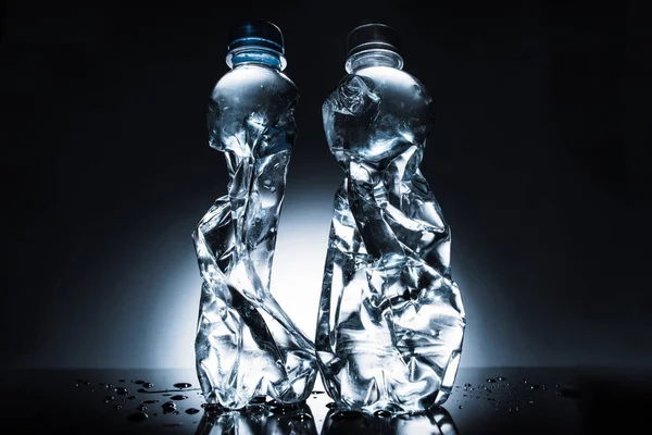 Still life with crumpled bottles of water on dark — Stock Photo