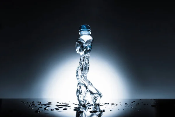 Bouteille d'eau en plastique froissé sur sombre — Photo de stock