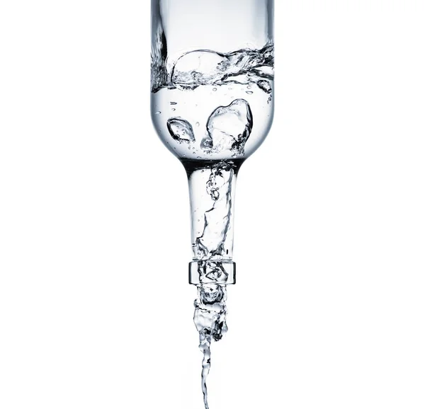 Plan rapproché de l'eau coulant d'une bouteille en verre isolée sur blanc — Photo de stock