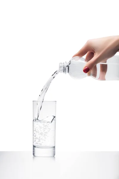 Tiro recortado de la mujer vertiendo agua en el vidrio de botella de plástico aislado en blanco - foto de stock