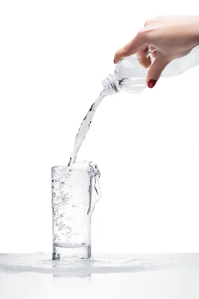 Colpo ritagliato di donna versando acqua nel vetro da bottiglia di plastica isolata su bianco — Foto stock