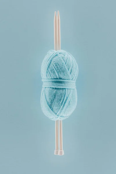 Вид сверху на голубой вязальный нитевидный шар с вязальными спицами, изолированный на голубом — стоковое фото