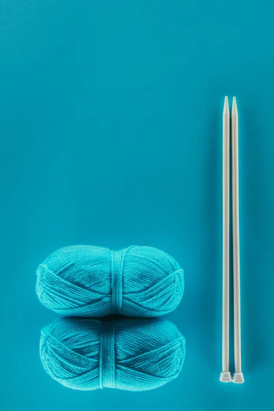 Vue du dessus des boules de fils à tricoter bleues avec aiguilles à tricoter, isolées sur bleu — Photo de stock