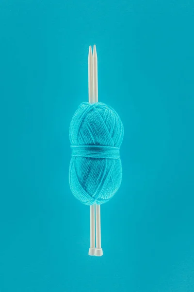 Вид зверху на синій в'язаний кульку з пряжею спицями, ізольований на синьому — стокове фото