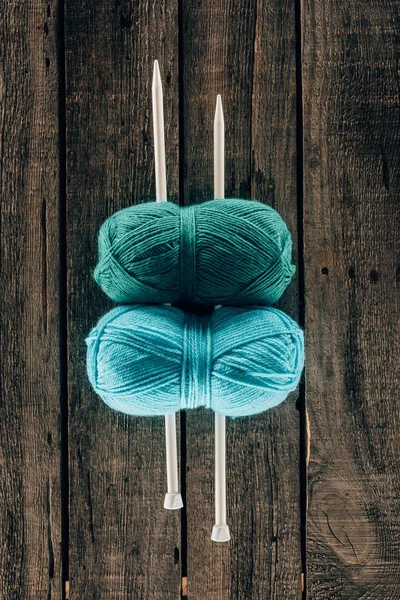 Top view of blue and green yarn with knitting needles on wooden background — Stock Photo