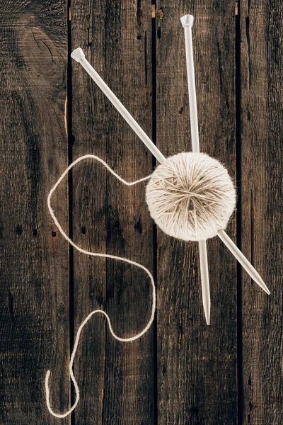 Top view of yarn ball with knitting needles on wooden background — Stock Photo