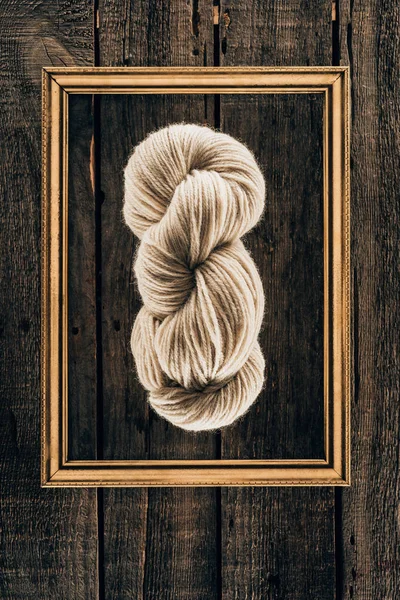 Top view of white knitting yarn with frame on wooden background — Stock Photo