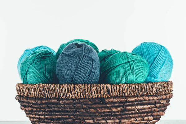 Blue and green warm yarn balls in wicker basket on white — Stock Photo