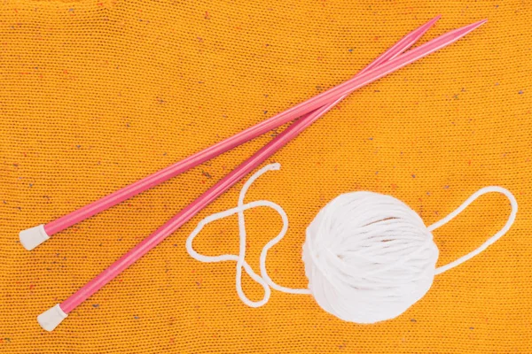 Vista superior de bola de fio branco e agulhas de tricô em malha amarela — Fotografia de Stock