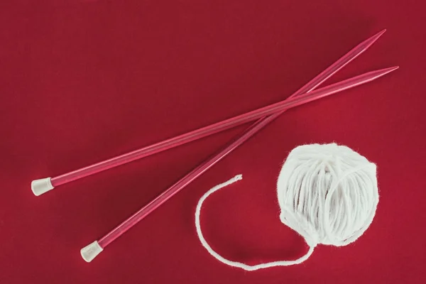 Top view of white wool ball and knitting needles, isolated on red — Stock Photo