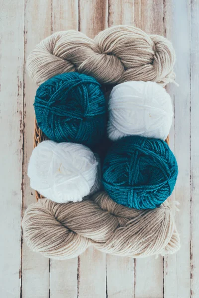 Top view of different knitting yarn balls in wicker basket on wooden background — Stock Photo