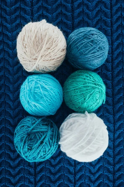 Vue de dessus de différentes boules de fil à tricoter sur le tricot bleu — Photo de stock