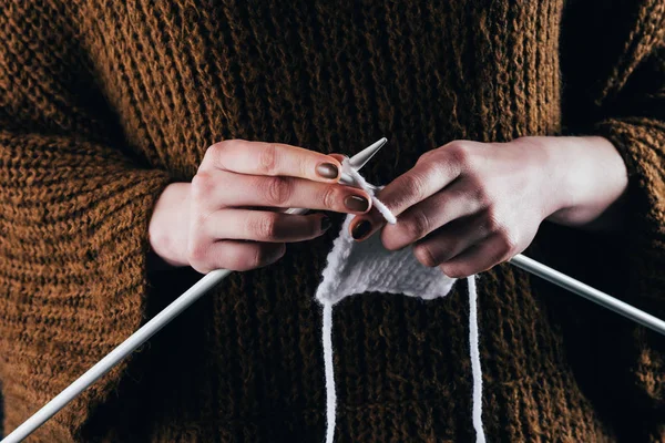 Cropped view of woman knitting white wool with needles — Stock Photo