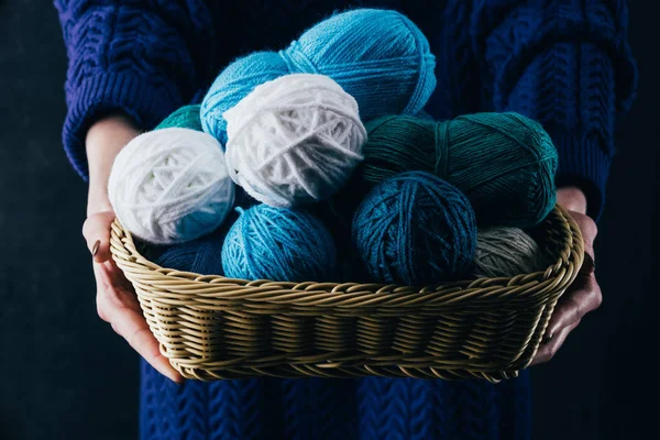 Cropped view of woman holding wicker basket with yarn balls — Stock Photo