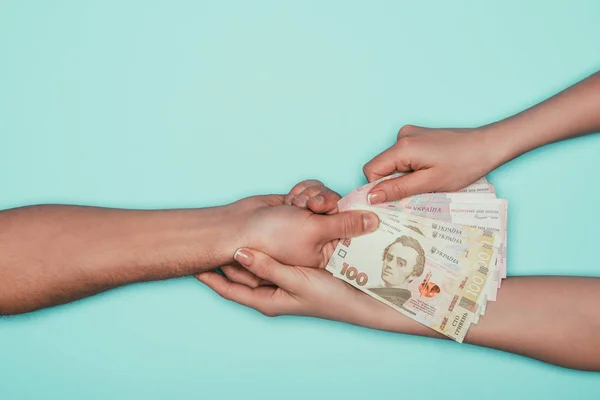 Обрезанный снимок женщины, берущей деньги у мужчины, изолированного от бирюзы — стоковое фото