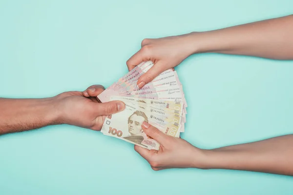Обрезанный снимок женщины, берущей деньги у мужчины, изолированного от бирюзы — стоковое фото