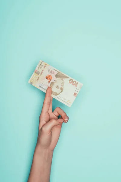 Cropped shot of woman holding ukrainian money isolated on turquoise — Stock Photo