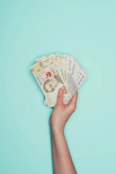 Cropped shot of holding bunch of ukrainian cash isolated on turquoise — Stock Photo