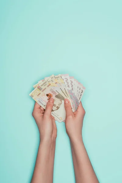 Cropped shot of holding bunch of ukrainian cash in hands isolated on turquoise — Stock Photo