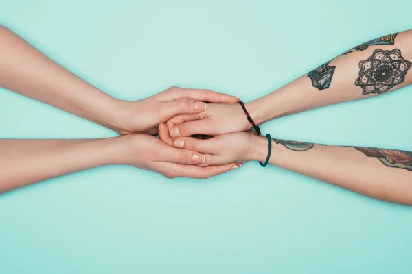 Abgeschnittene Aufnahme sinnlicher Frauen, die einander die Hände halten, isoliert auf Türkis — Stockfoto