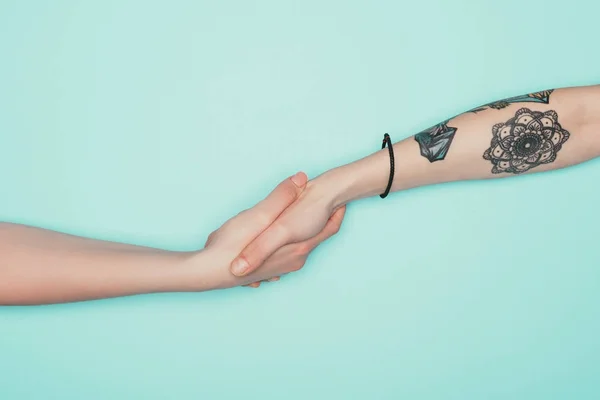 Cropped shot of women shaking hands isolated on turquoise — Stock Photo