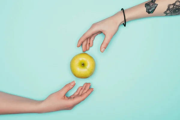 Обрізаний знімок жінок, що проходять зелене яблуко ізольовано на бірюзовому — стокове фото
