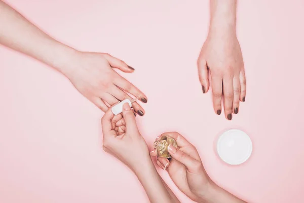 Recortado tiro de manicura aplicando esmalte en las uñas de cliente aislado en rosa - foto de stock