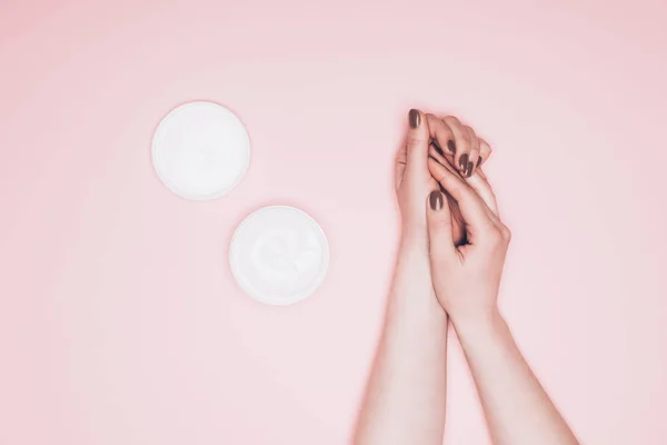 Tiro recortado de la mujer aplicando crema de manos aislado en rosa - foto de stock