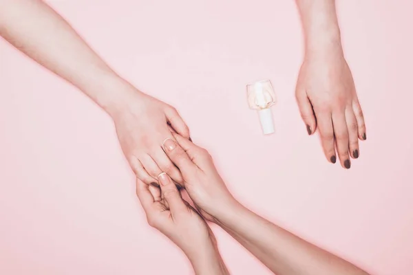 Cropped shot of manicurist holdign hand of client isolated on pink — Stock Photo