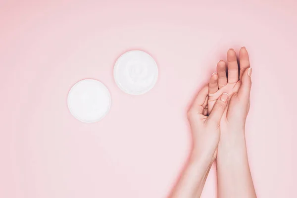 Tiro recortado de la mujer aplicando crema hidratante en la mano aislado en rosa - foto de stock