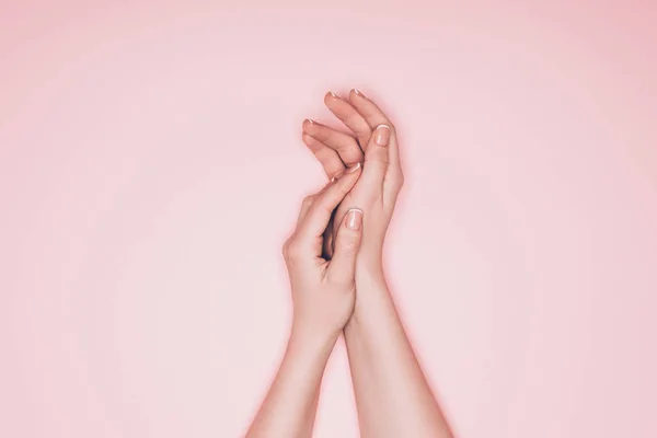 Tiro recortado de las manos femeninas con la piel perfecta aislada en rosa - foto de stock
