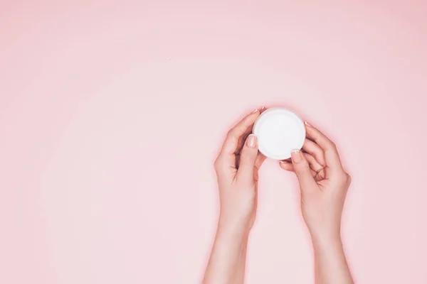 Tiro recortado de mujer sosteniendo abierto lata de crema hidratante aislado en rosa - foto de stock