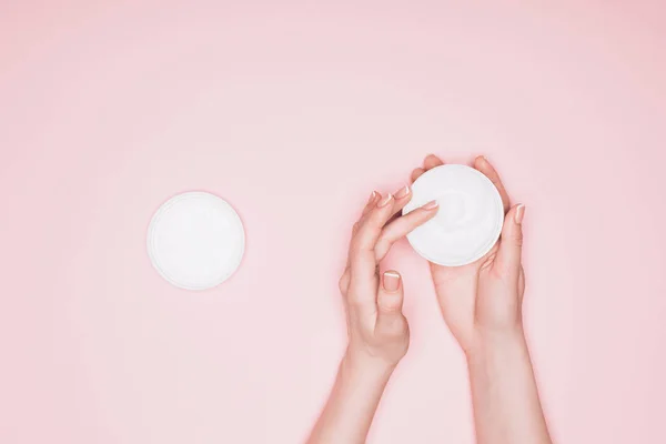 Schnappschuss einer Frau, die Feuchtigkeitscreme aus Dose nimmt, isoliert auf rosa — Stockfoto