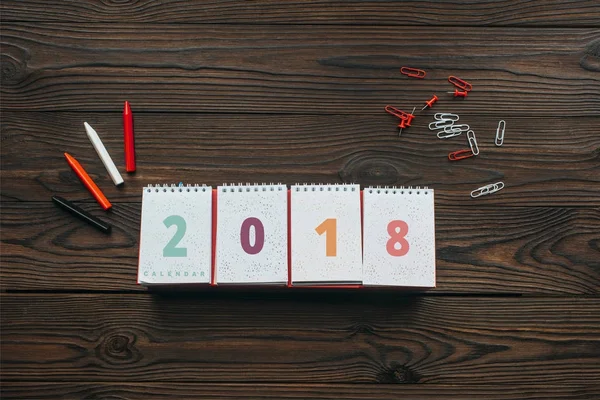 Top view of 2018 calendar, pencils and stationery on wooden tabletop — Stock Photo