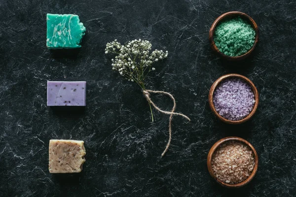 Vue de dessus du savon fait maison, fleurs séchées et sel de mer sur la surface de marbre noir, concept de spa — Photo de stock