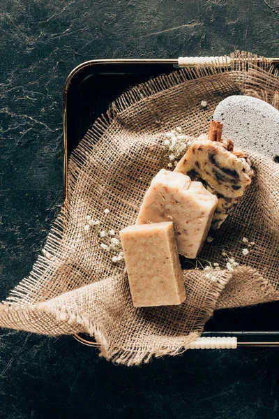 Vue de dessus de savon naturel fait maison et pierre ponce pour spa sur sac en plateau — Photo de stock