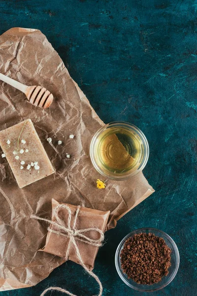 Top view of natural soap, oil and coffee scrub for spa on crumpled paper on green marble surface — Stock Photo