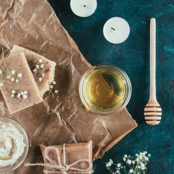 Vista dall'alto di sapone artigianale naturale miele e gocciolatore per spa su carta sgualcita su superficie di marmo verde — Foto stock