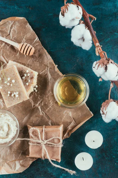 Flat lay with natural soap, oil, salt scrub and cotton flower on crumpled paper on green marble surface — Stock Photo