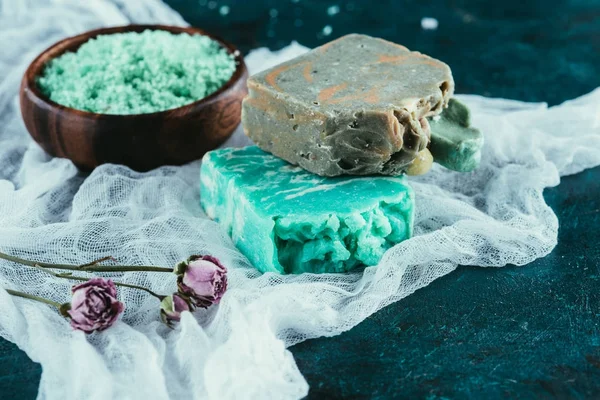 Homemade soap, dried roses and sea salt for spa on white gauze on marble surface — Stock Photo