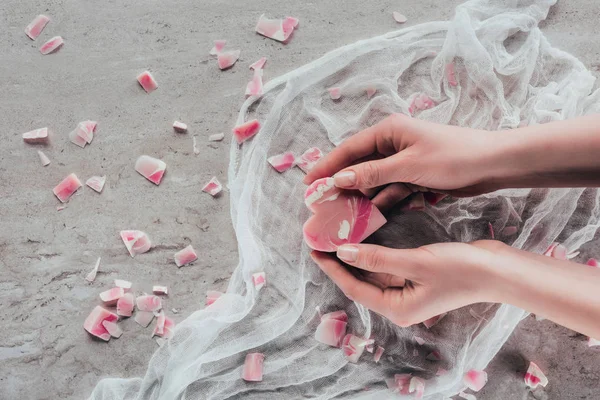 Vue recadrée des mains avec savon rose en forme de coeur sur gaze blanche à la surface du marbre — Photo de stock