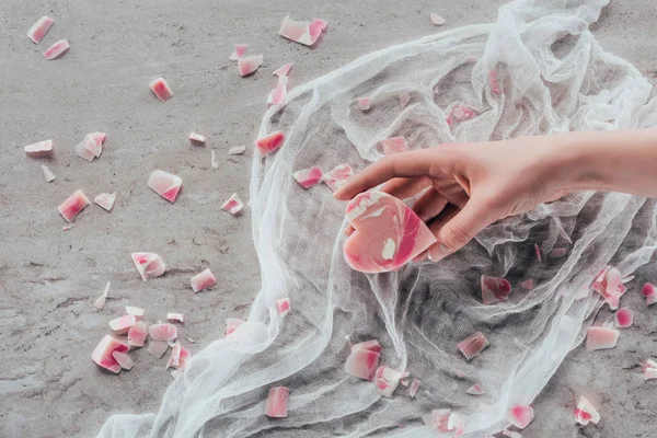 Обрізаний вид жіночої руки з рожевим милом у формі серця на білій марлі на мармуровій поверхні — стокове фото