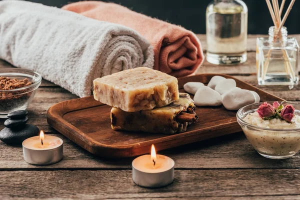 Serviettes, savon maison, soins spa et bougies sur table en bois — Photo de stock