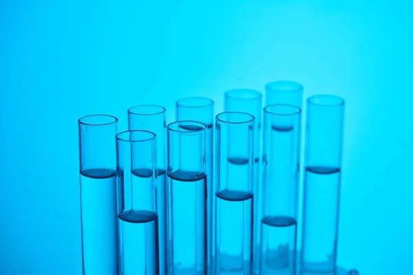 Tubi di vetro con liquido per prove chimiche su blu — Foto stock