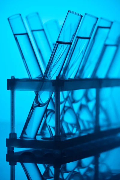 Glass tubes with liquid on stand in chemical laboratory on blue — Stock Photo